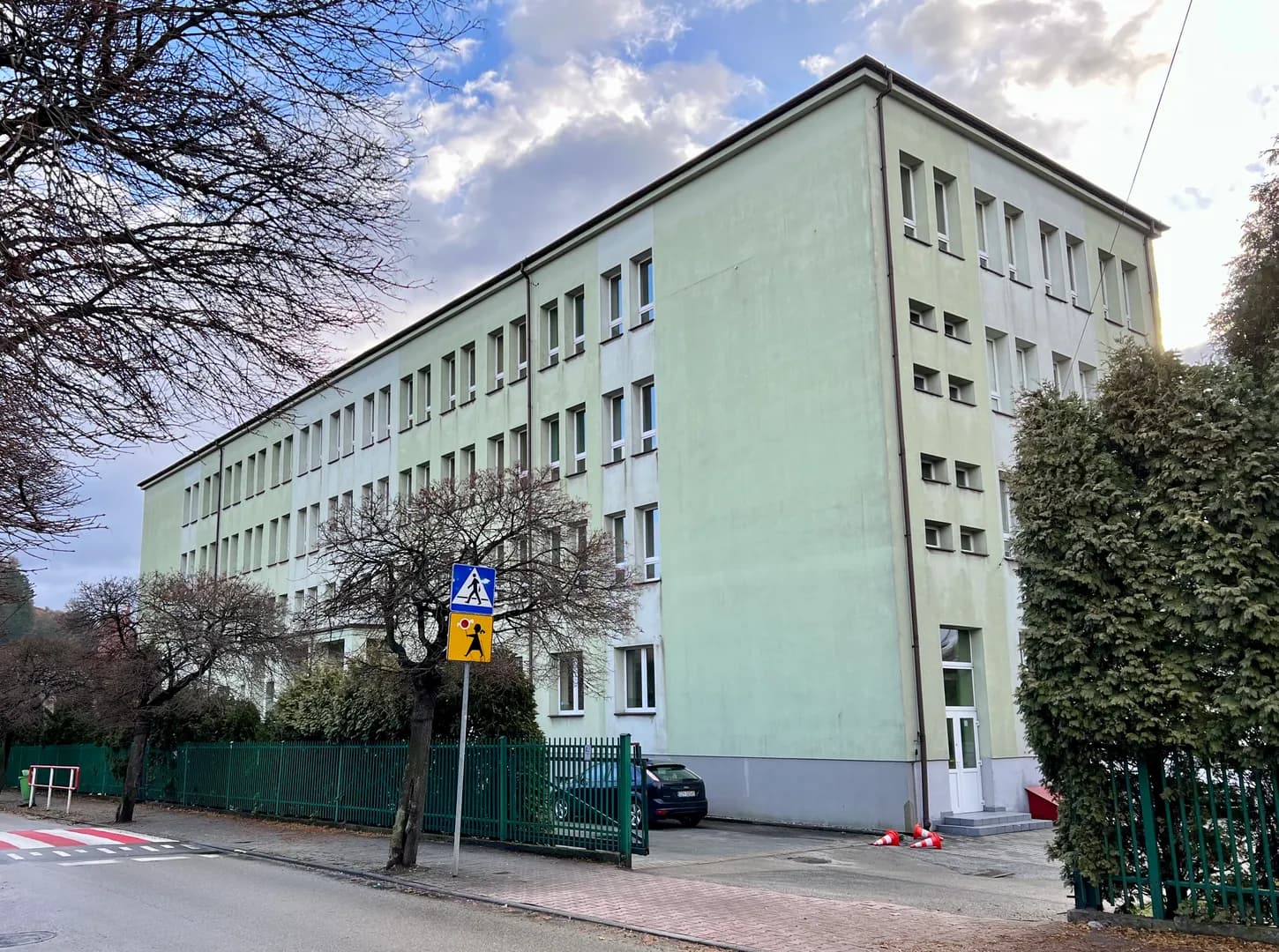 Elewacja budynku Szkoły Podstawowej nr 1 w Żywcu widoczna zza ogrodzenia.