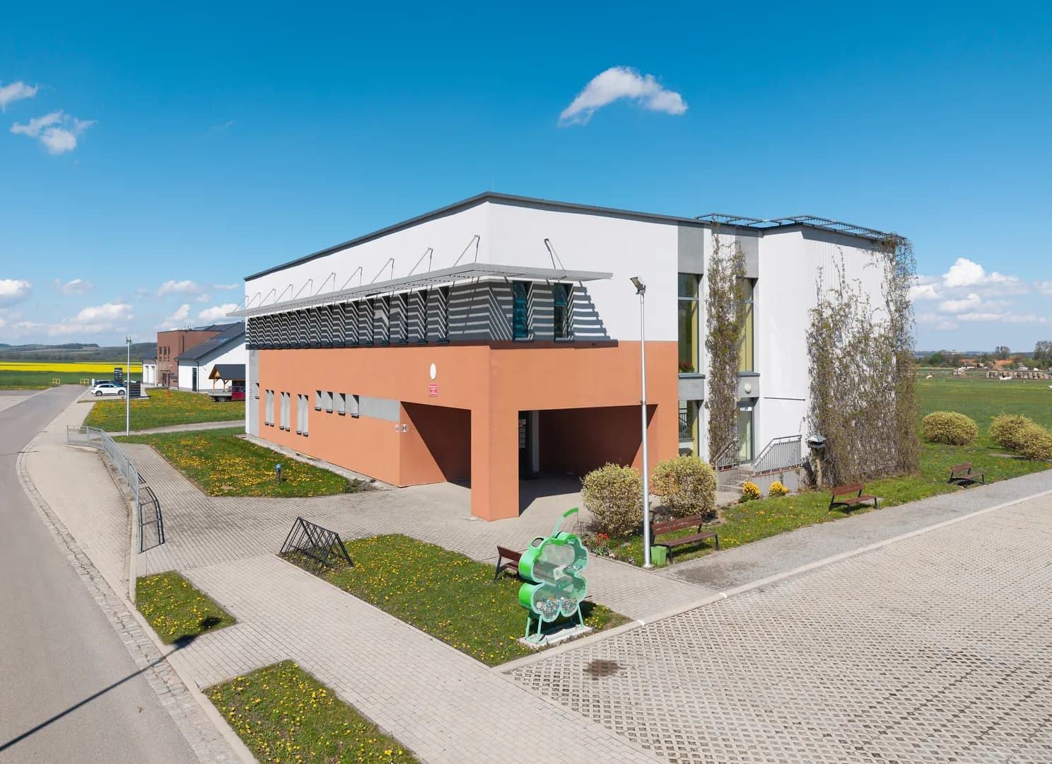Nowoczesny budynek Szkoły Podstawowej w Budzowie z placem i zielenią