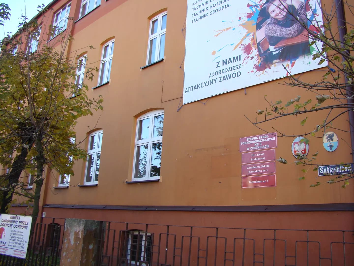 Elewacja budynku Technikum nr 3 w Chojnicach z tablicami informacyjnymi i banerem