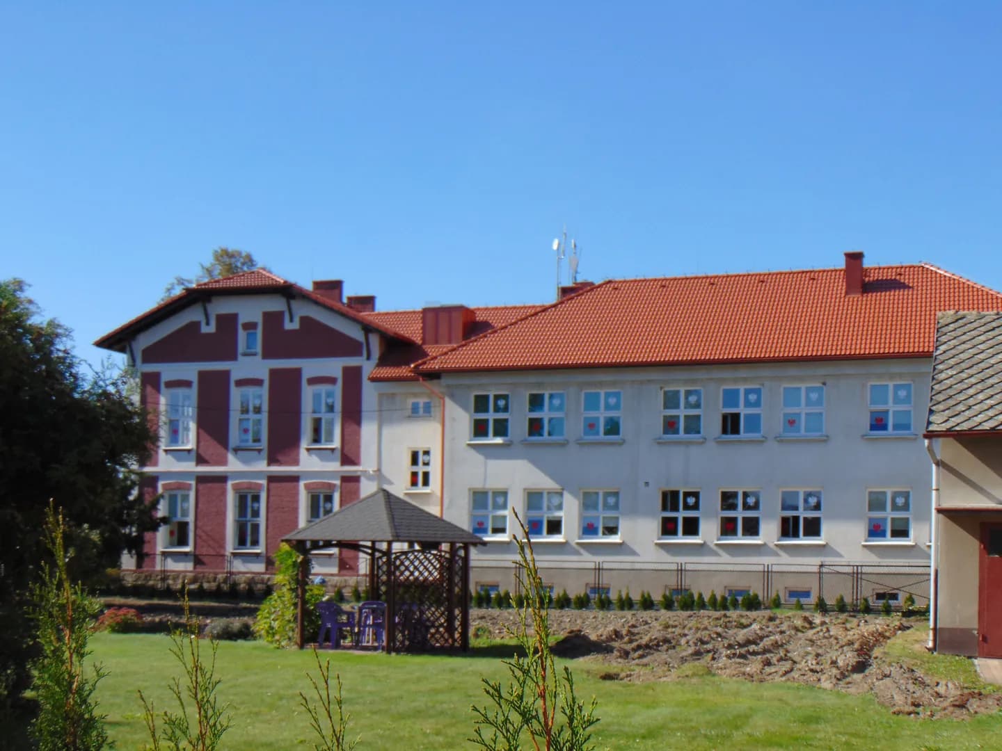Budynek Zespołu Szkolno-Przedszkolnego w Hecznarowicach z altaną ogrodową na pierwszym planie