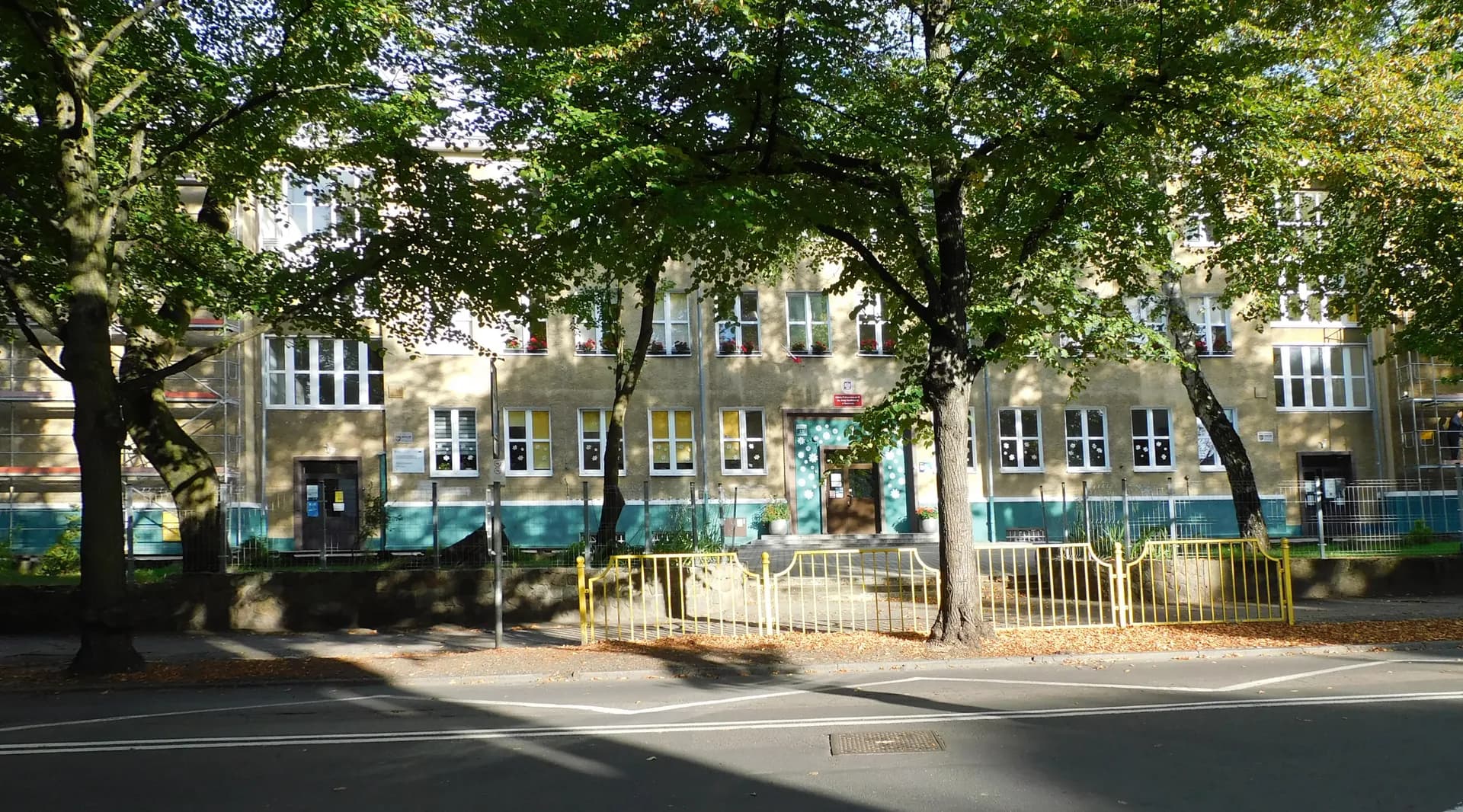 Fasada budynku Szkoły Podstawowej nr 46 w Szczecinie widoczna zza drzew.