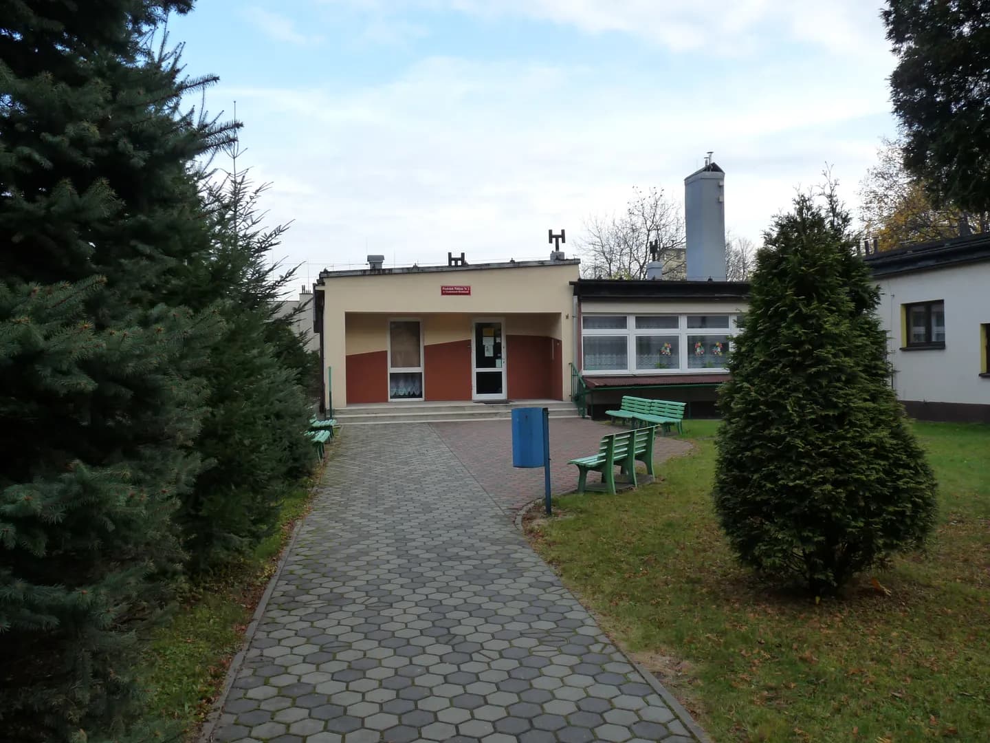 Wejście do Przedszkola Publicznego nr 2 w Czechowicach-Dziedzicach z chodnikiem i zielenią.