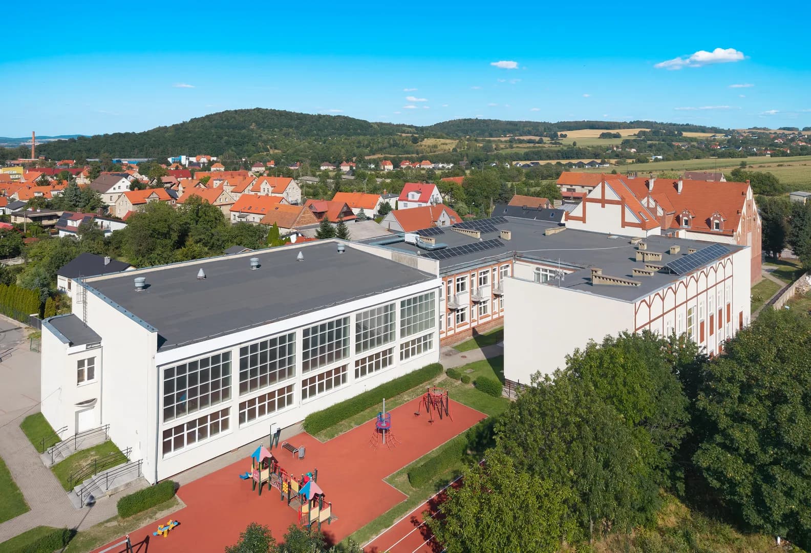 Widok z góry na kompleks budynków Szkoły Podstawowej nr 4 w Bielawie i plac zabaw