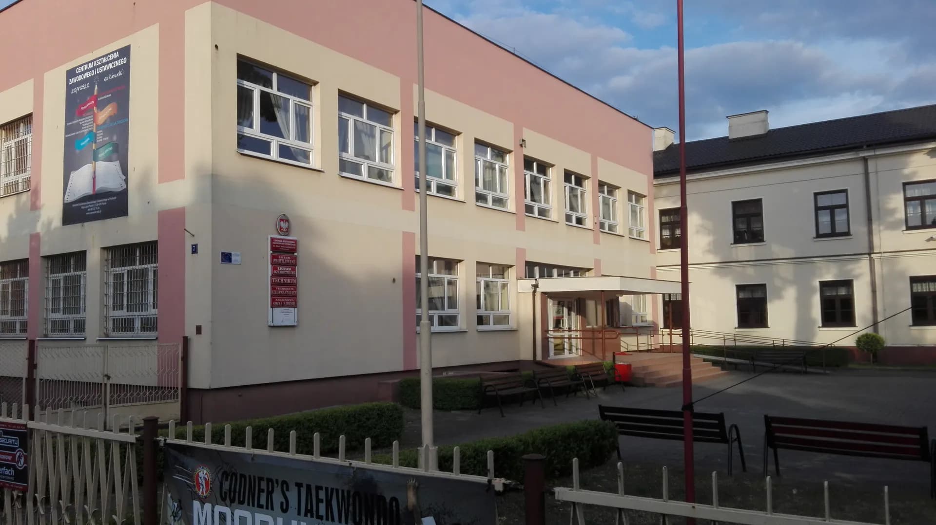 Budynek szkoły w Pionkach z wejściem głównym i placem przed nim