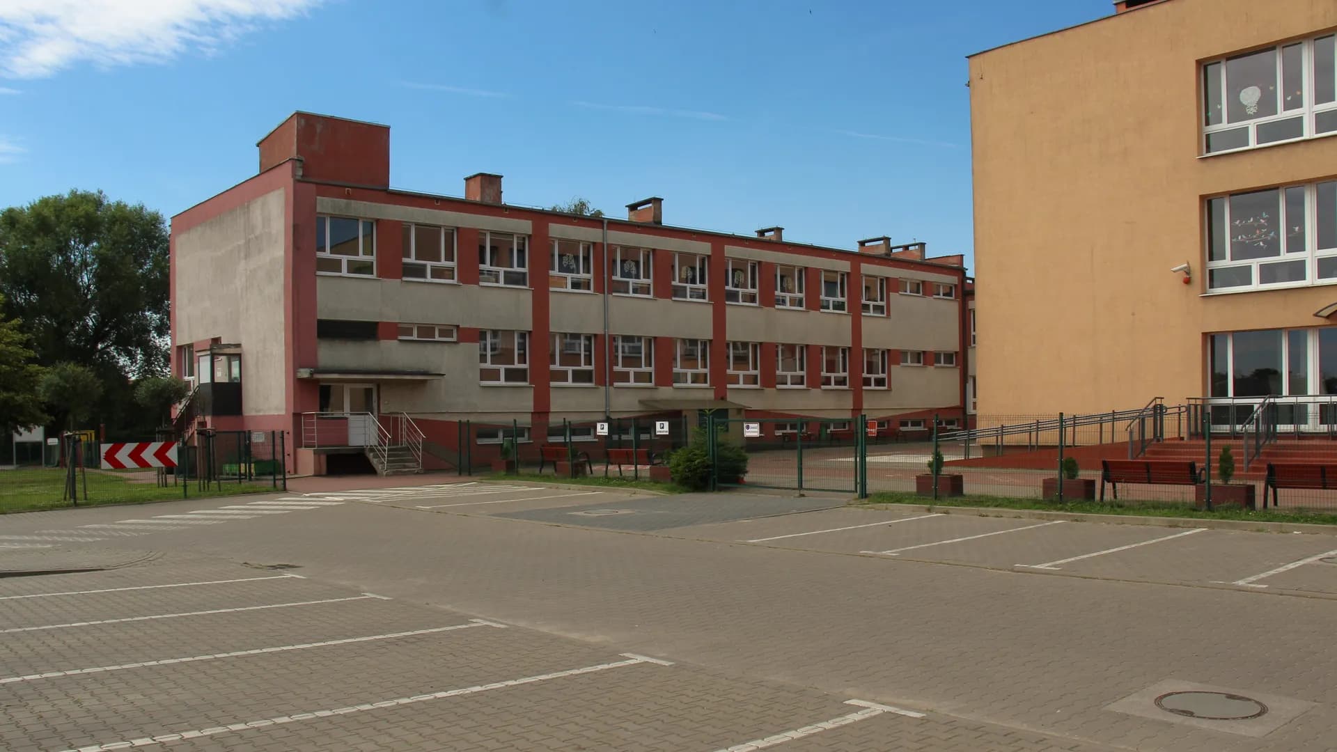 Budynek Zespołu Szkolno-Przedszkolnego w Dopiewie z parkingiem na pierwszym planie