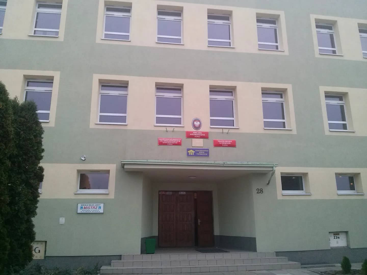 Wejście do budynku Publicznego Liceum Ogólnokształcącego nr III w Opolu z tablicami informacyjnymi.
