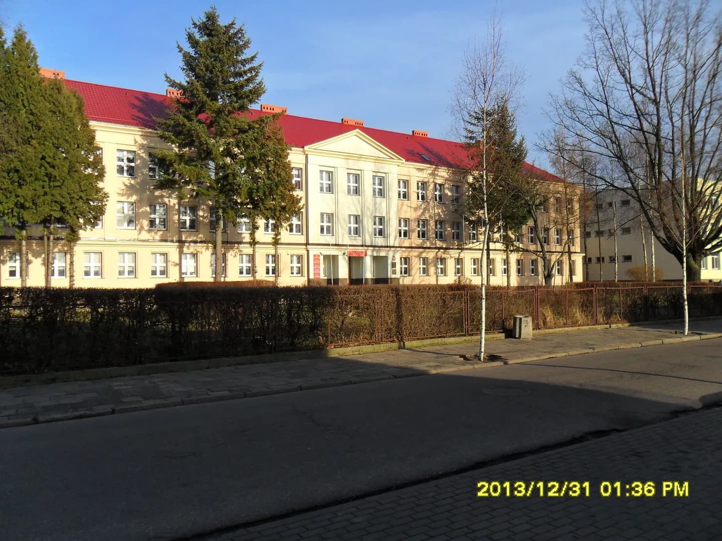 Budynek Zespołu Szkół nr 1 im. Bolesława Krzywoustego w Choszcznie widoczny zza ulicy i ogrodzenia.
