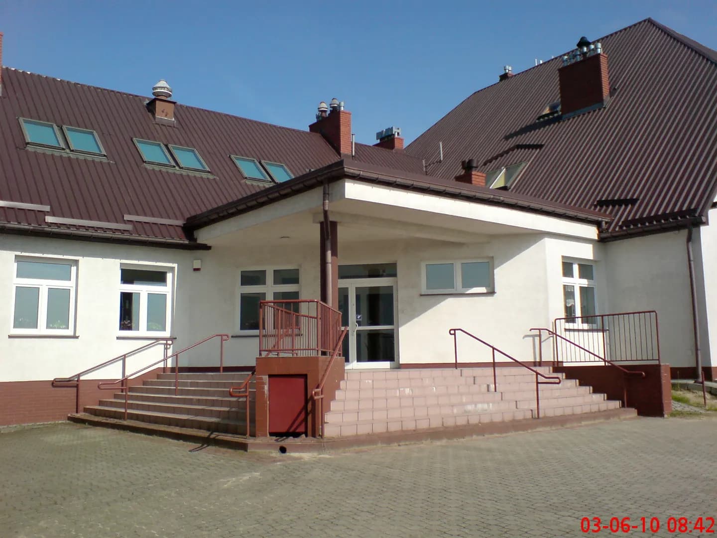 Wejście do Zespołu Szkół w Wólce Niedźwiedzkiej ze schodami i brązowym dachem