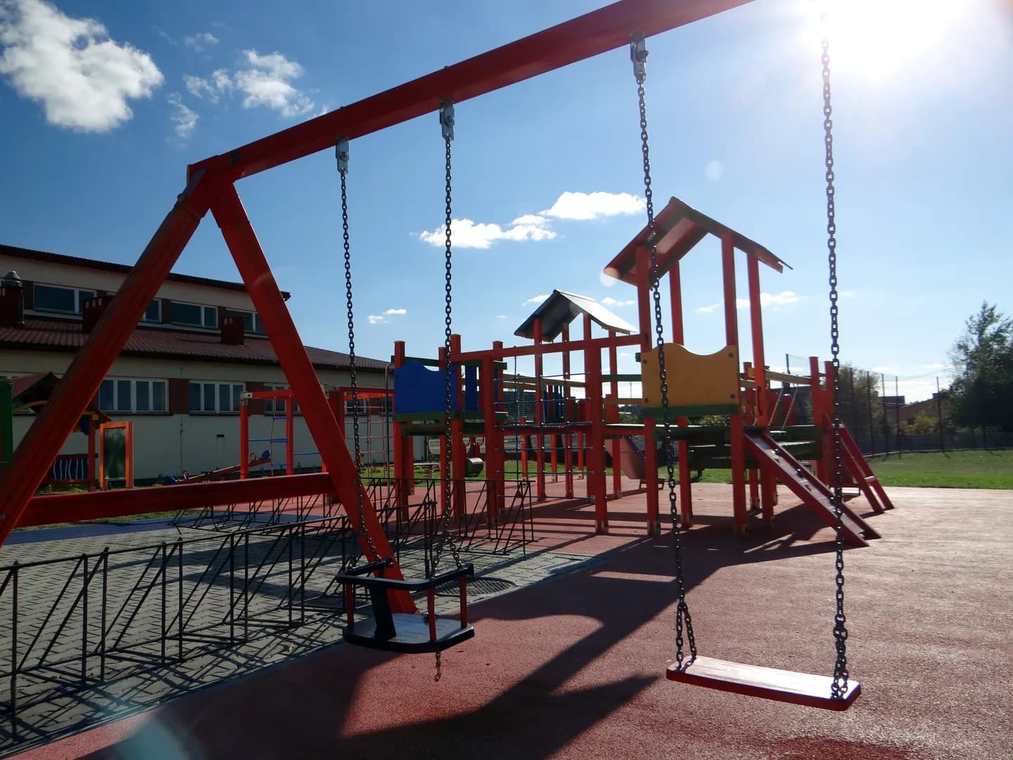 Plac zabaw przy szkole w Groblach z huśtawkami i drewnianą konstrukcją