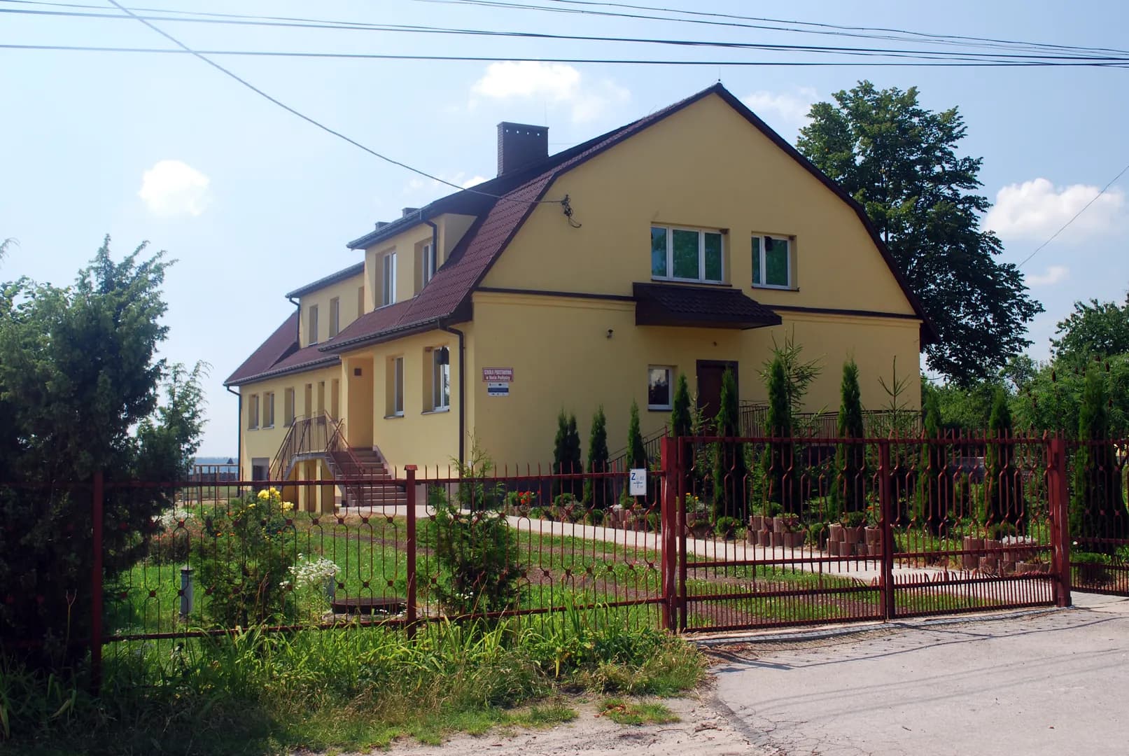 Budynek Szkoły Podstawowej w Hucie Podłysicy z widocznym ogrodzeniem