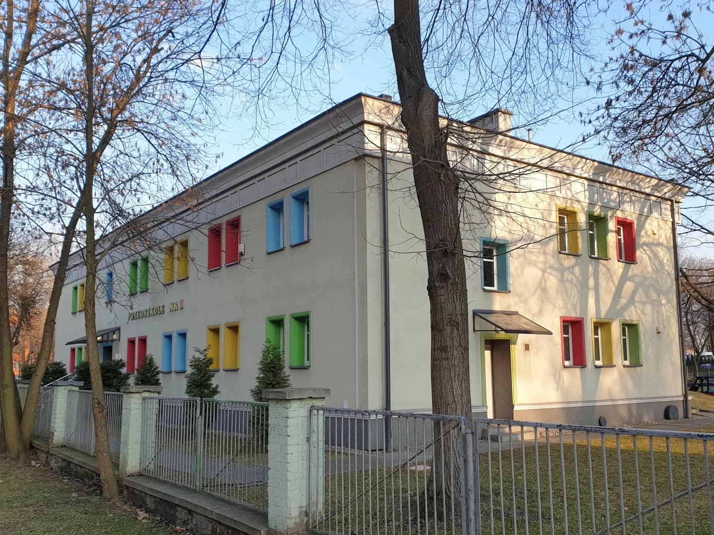 Budynek Przedszkola nr 1 w Zabrzu z kolorowymi obramowaniami okien widziany zza ogrodzenia