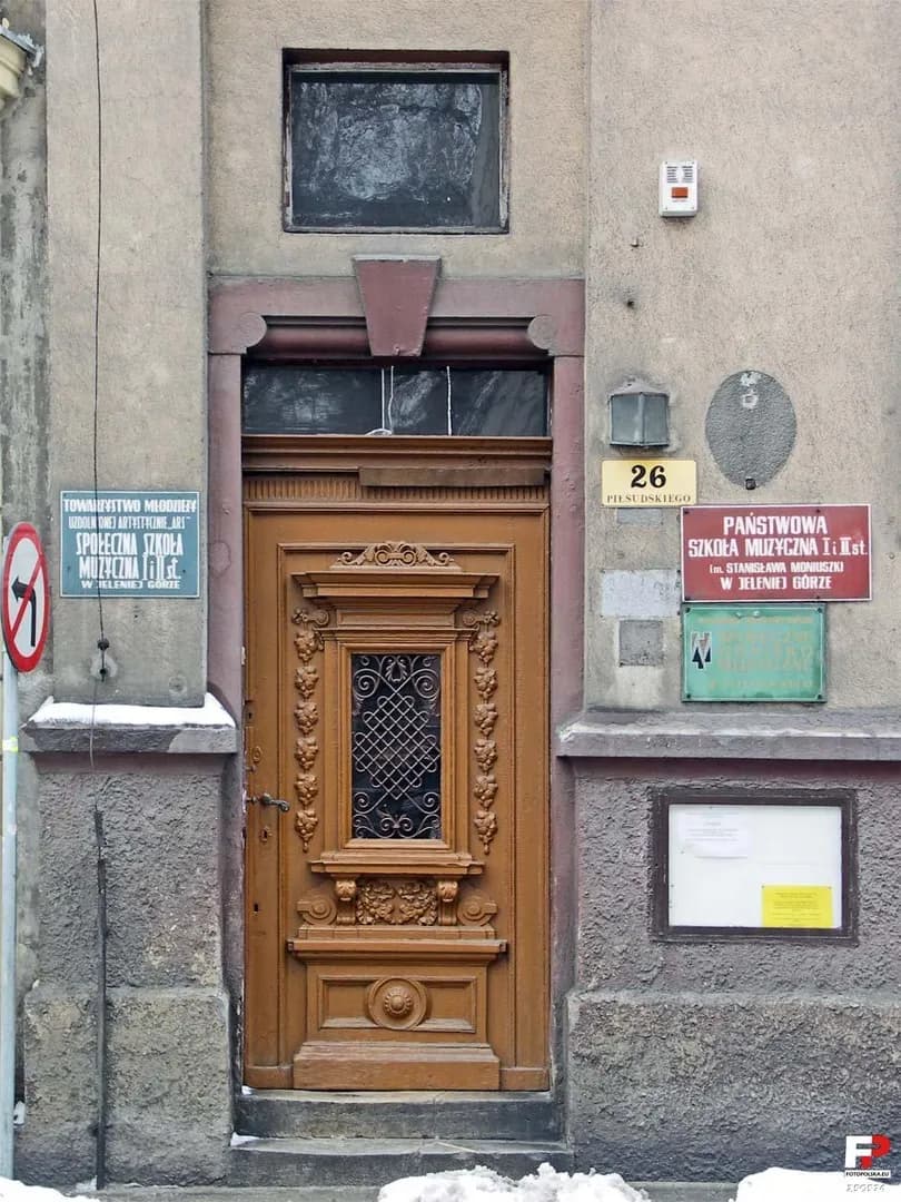 Drzwi wejściowe do Państwowej Szkoły Muzycznej I i II stopnia w Jeleniej Górze z tablicami informacyjnymi