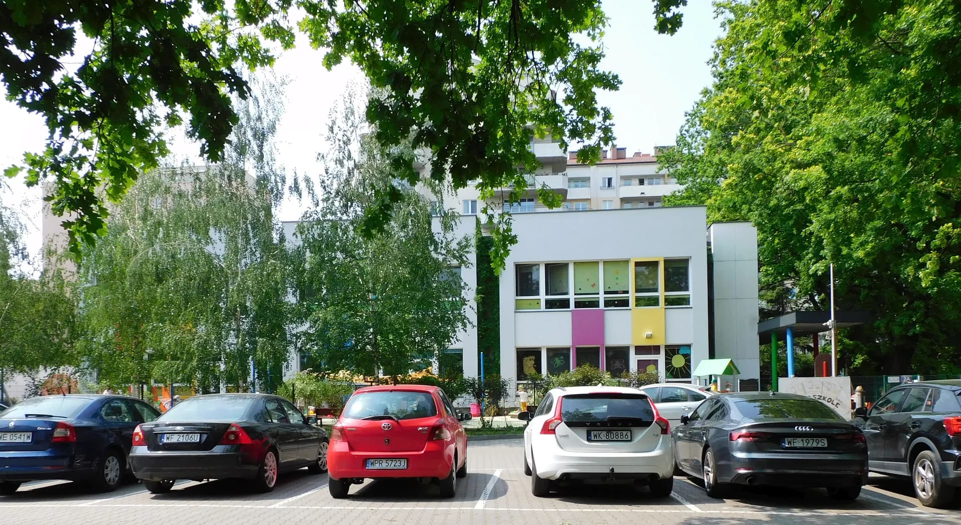 Budynek Przedszkola nr 439 w Warszawie widoczny zza parkingu samochodowego