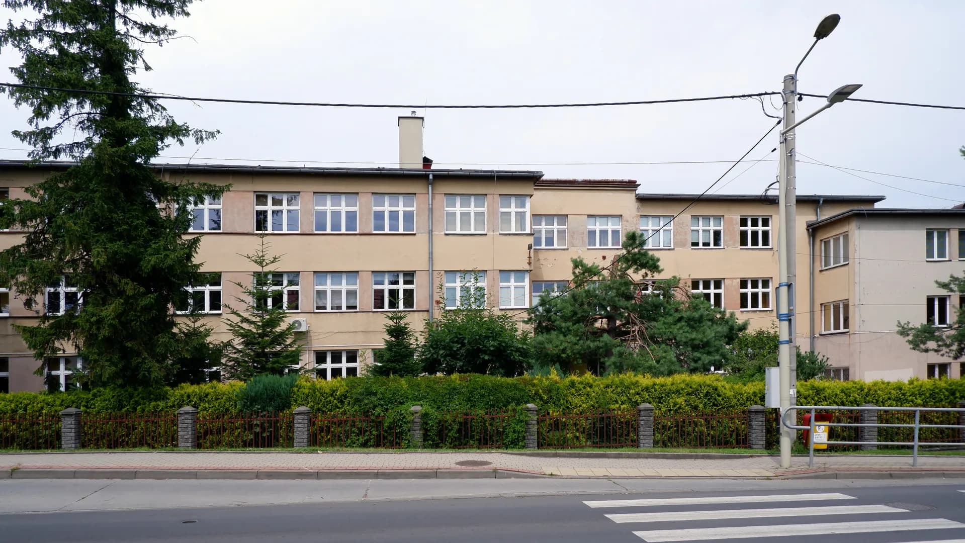 Elewacja budynku Szkoły Podstawowej nr 30 w Bielsku-Białej widziana zza ogrodzenia.