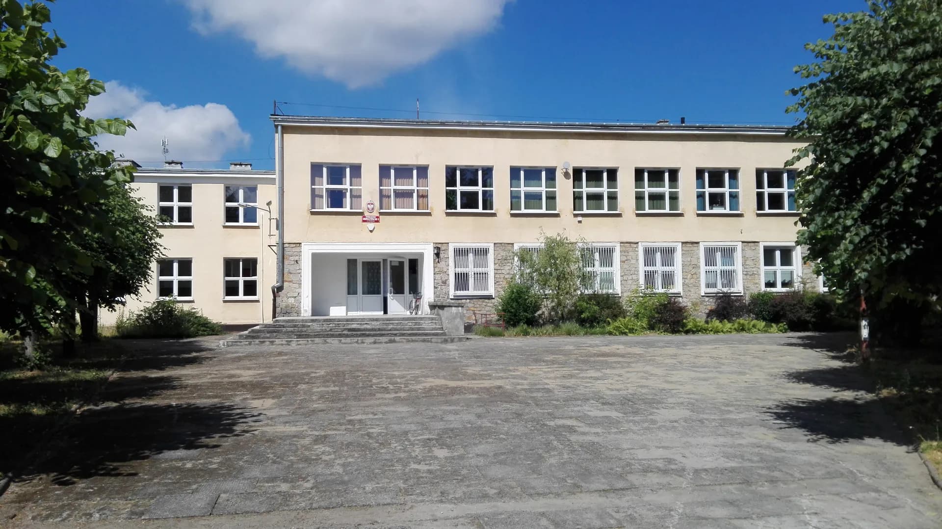 Fasada budynku szkoły przy ulicy Leśnej w Pionkach wraz z placem przed wejściem