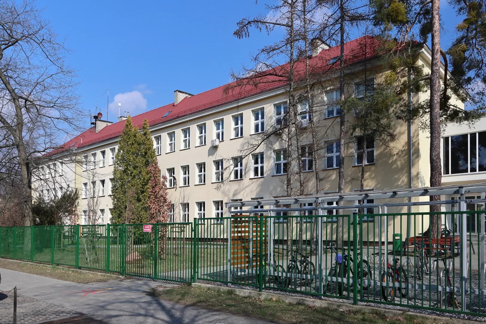 Budynek Szkoły Podstawowej nr 218 im. Michała Kajki w Warszawie widoczny zza ogrodzenia