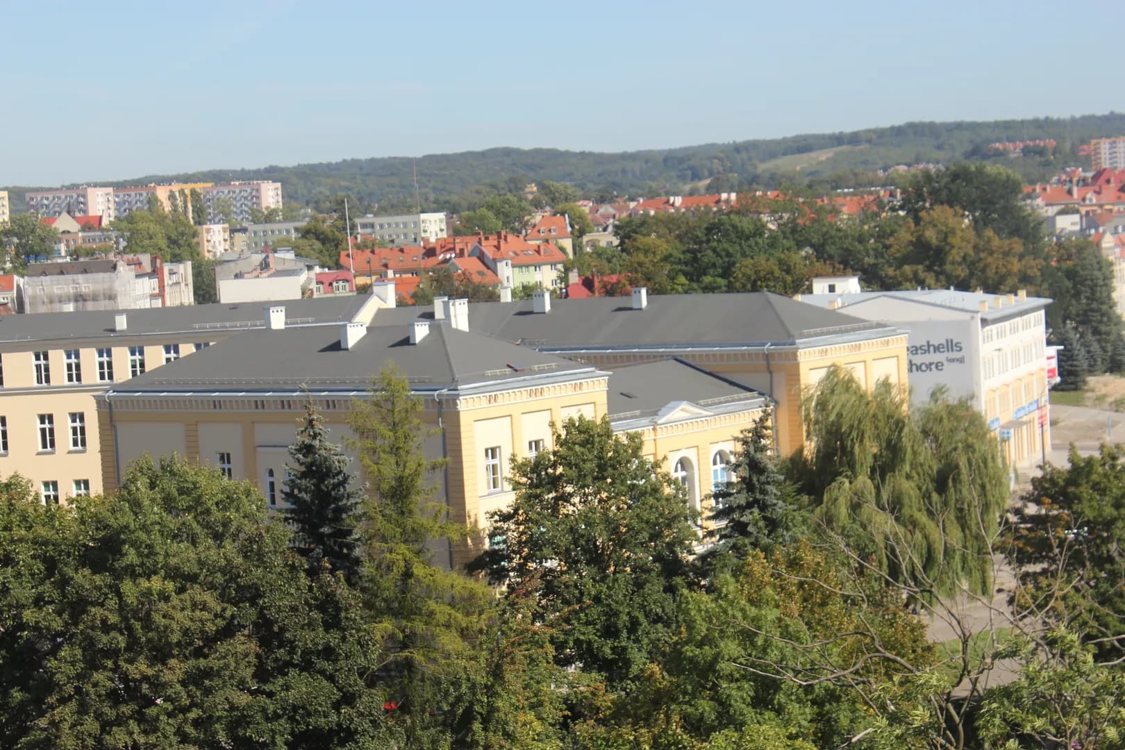 Kompleks budynków I LO w Elblągu widoczny z góry spoza koron drzew
