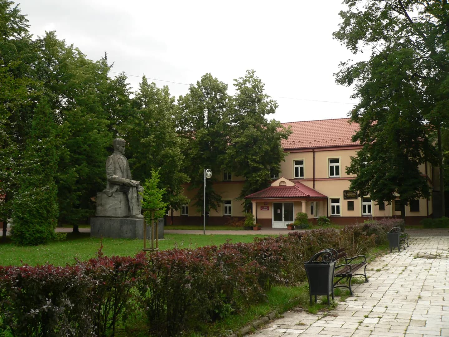 Teren IV Liceum Ogólnokształcącego w Częstochowie z pomnikiem patrona i budynkiem szkoły