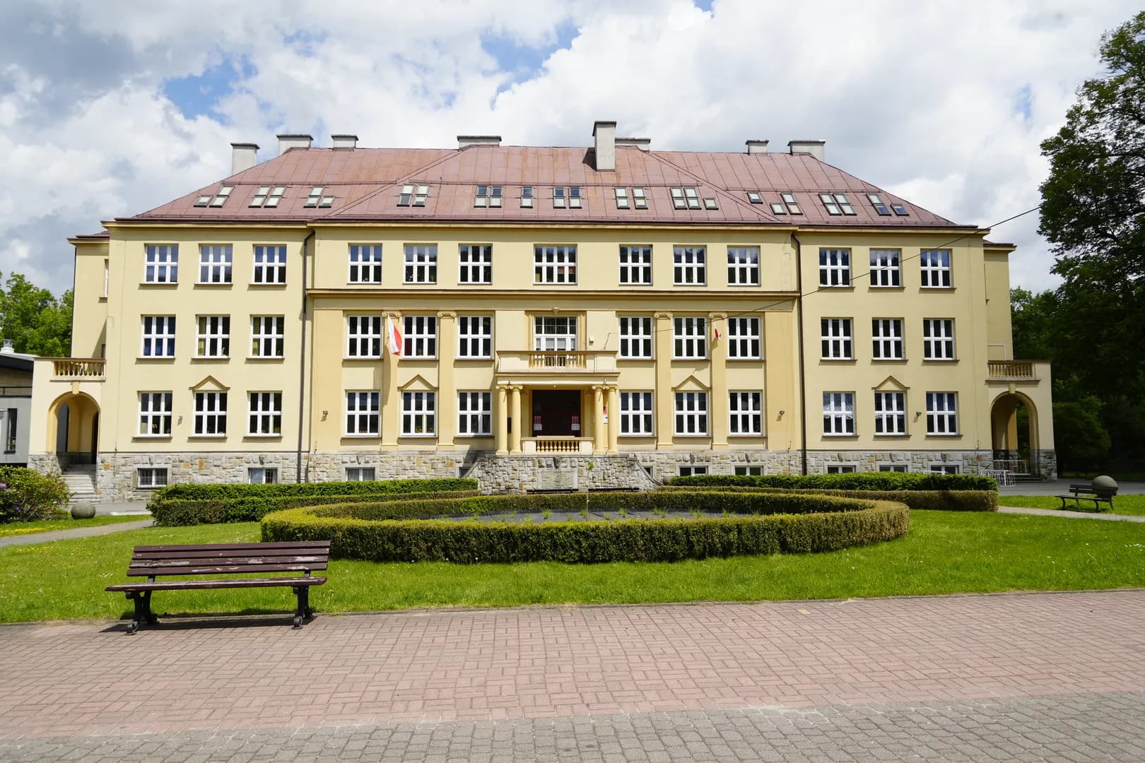 Fasada budynku I Liceum Ogólnokształcącego im. Pawła Stalmacha w Wiśle z widokiem na skwer