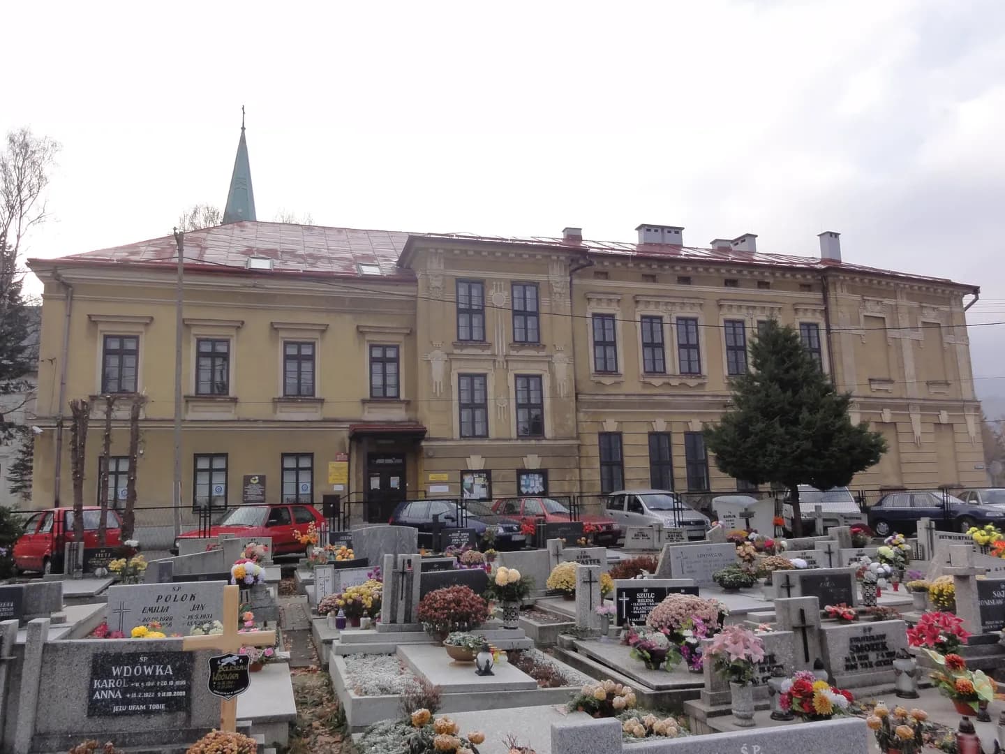 Zabytkowy budynek szkoły w Ustroniu widoczny zza terenu cmentarza