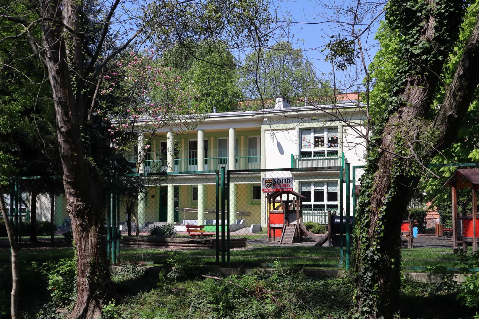 Budynek Przedszkola nr 9 w Warszawie z widocznym ogrodem i placem zabaw