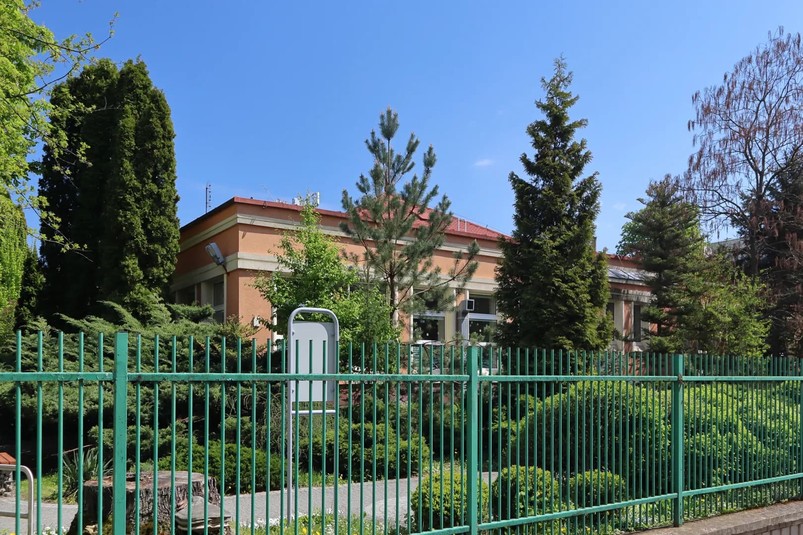 Budynek Przedszkola nr 10 w Warszawie widziany zza ogrodzenia i drzew