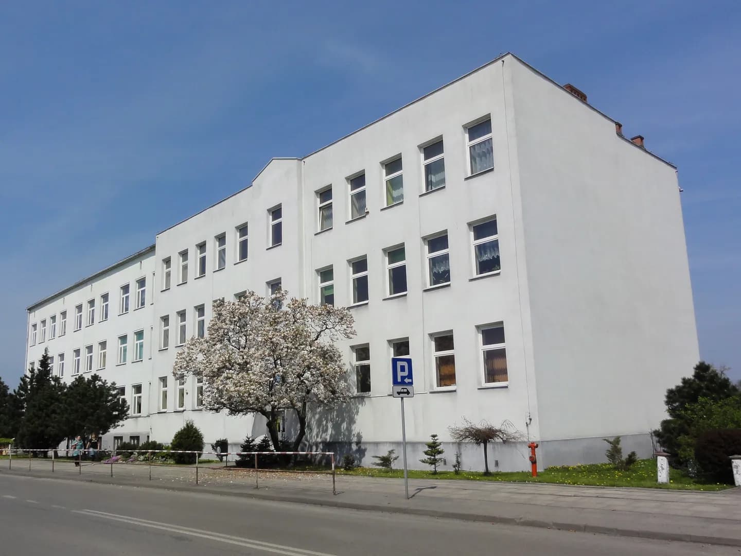 Jasny budynek Szkoły Podstawowej nr 1 w Chybiu widziany od strony ulicy.