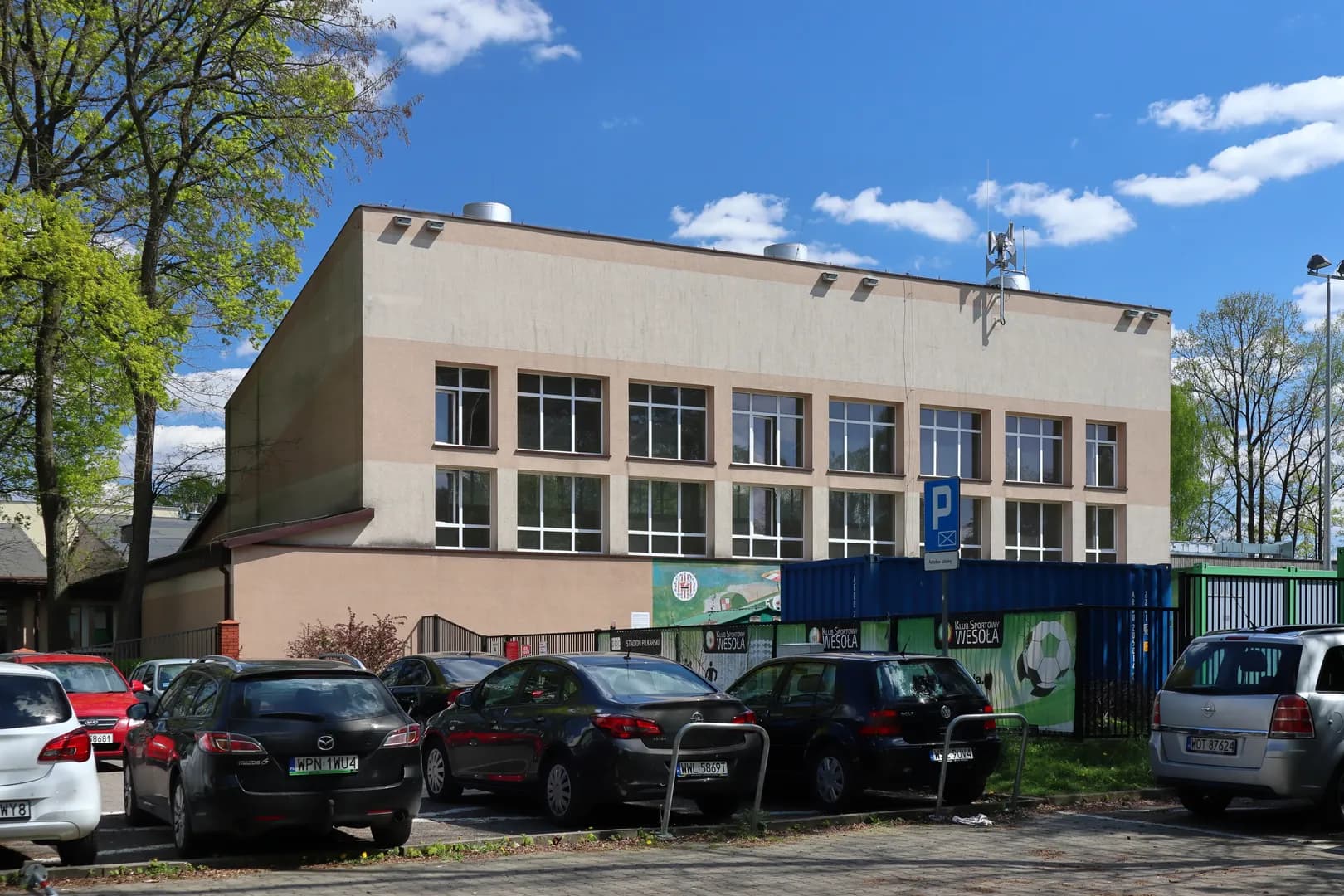 Budynek sali gimnastycznej Szkoły Podstawowej nr 174 w Warszawie widziany z parkingu.