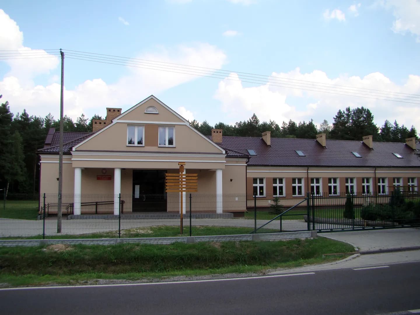 Budynek Szkoły Podstawowej w Kaczórkach widoczny zza ogrodzenia