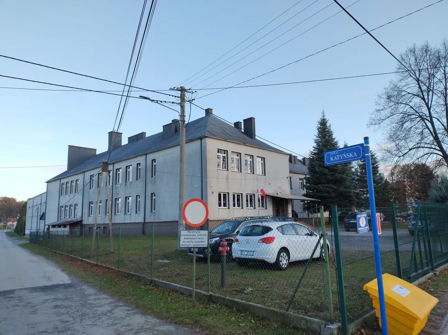 Budynek Zespołu Szkół w Dzikowcu widziany zza ogrodzenia przy ulicy Katyńskiej.