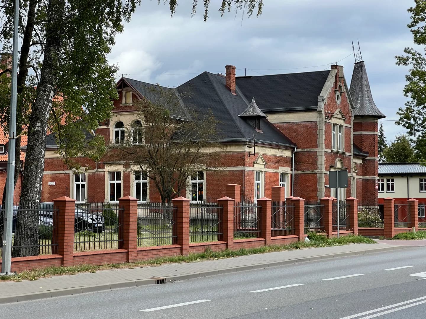 Zabytkowy budynek Specjalnego Ośrodka Szkolno-Wychowawczego w Węgorzewie z cegły za ogrodzeniem