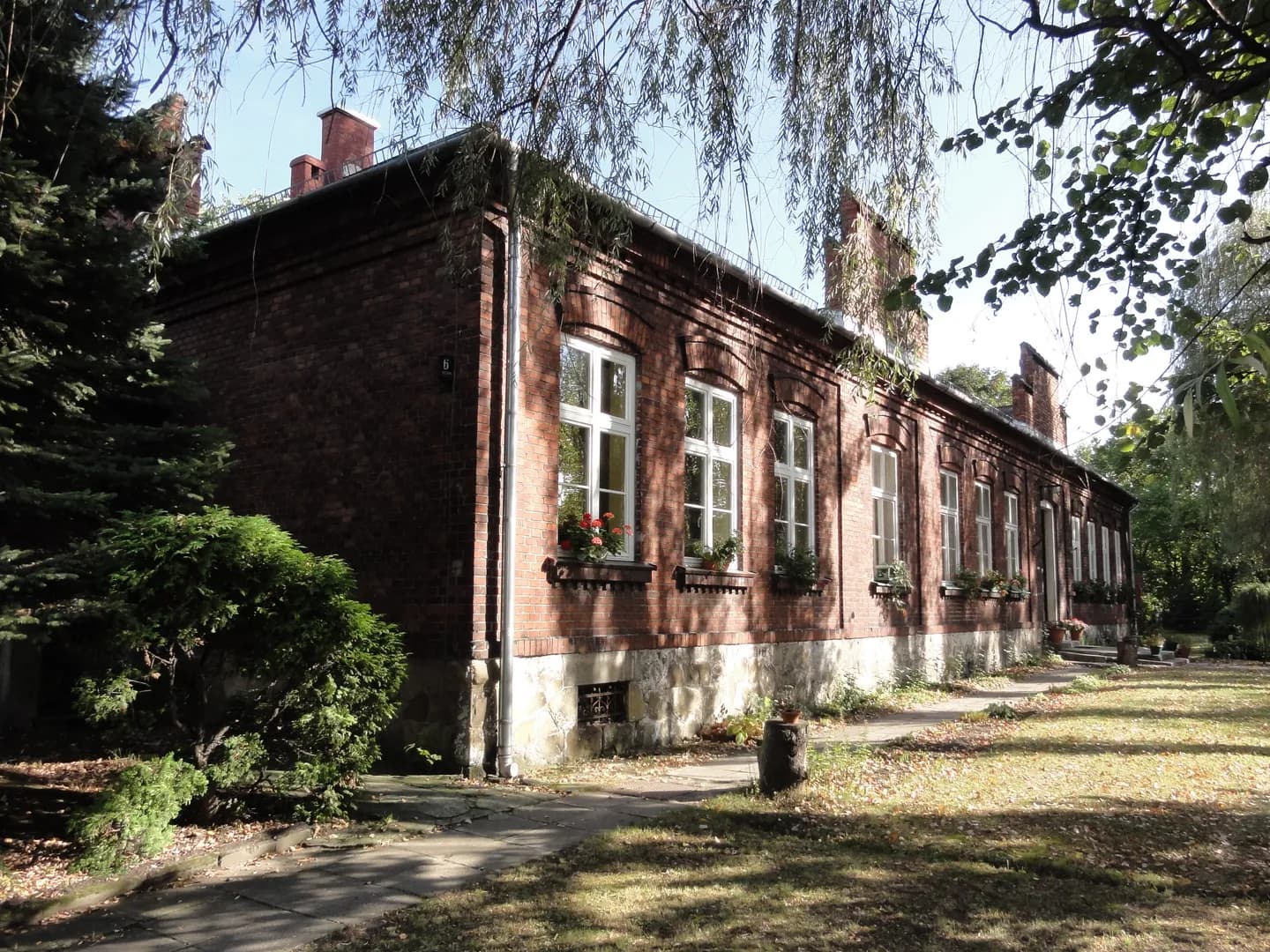 Zabytkowy ceglany budynek Przedszkola nr 26 w Bielsku-Białej otoczony drzewami
