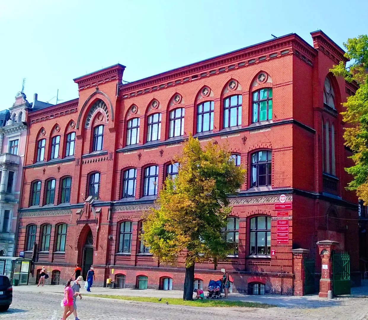Ceglany budynek Centrum Kształcenia Ustawicznego w Toruniu widoczny od strony ulicy