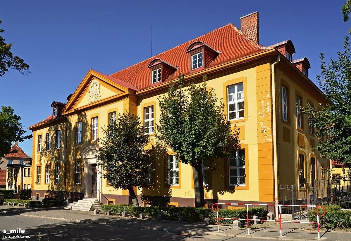 Zabytkowy żółty budynek Szkoły Podstawowej nr 1 w Kowarach w słoneczny dzień