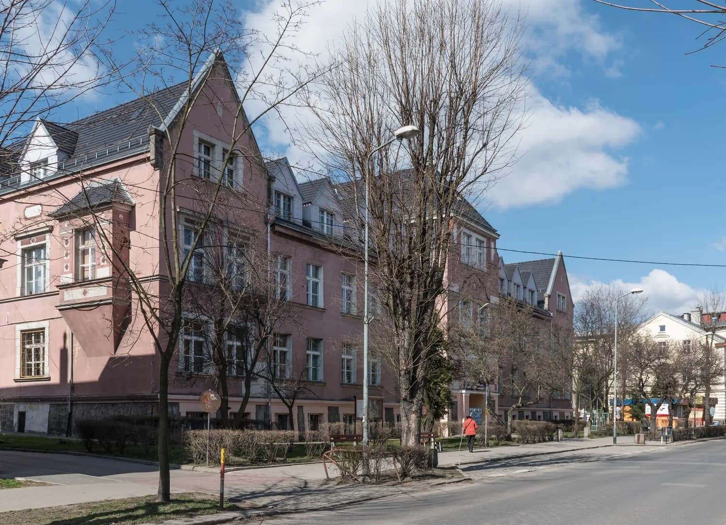 Gmach Zespołu Szkół Technicznych w Kłodzku widoczny zza drzew przy ulicy