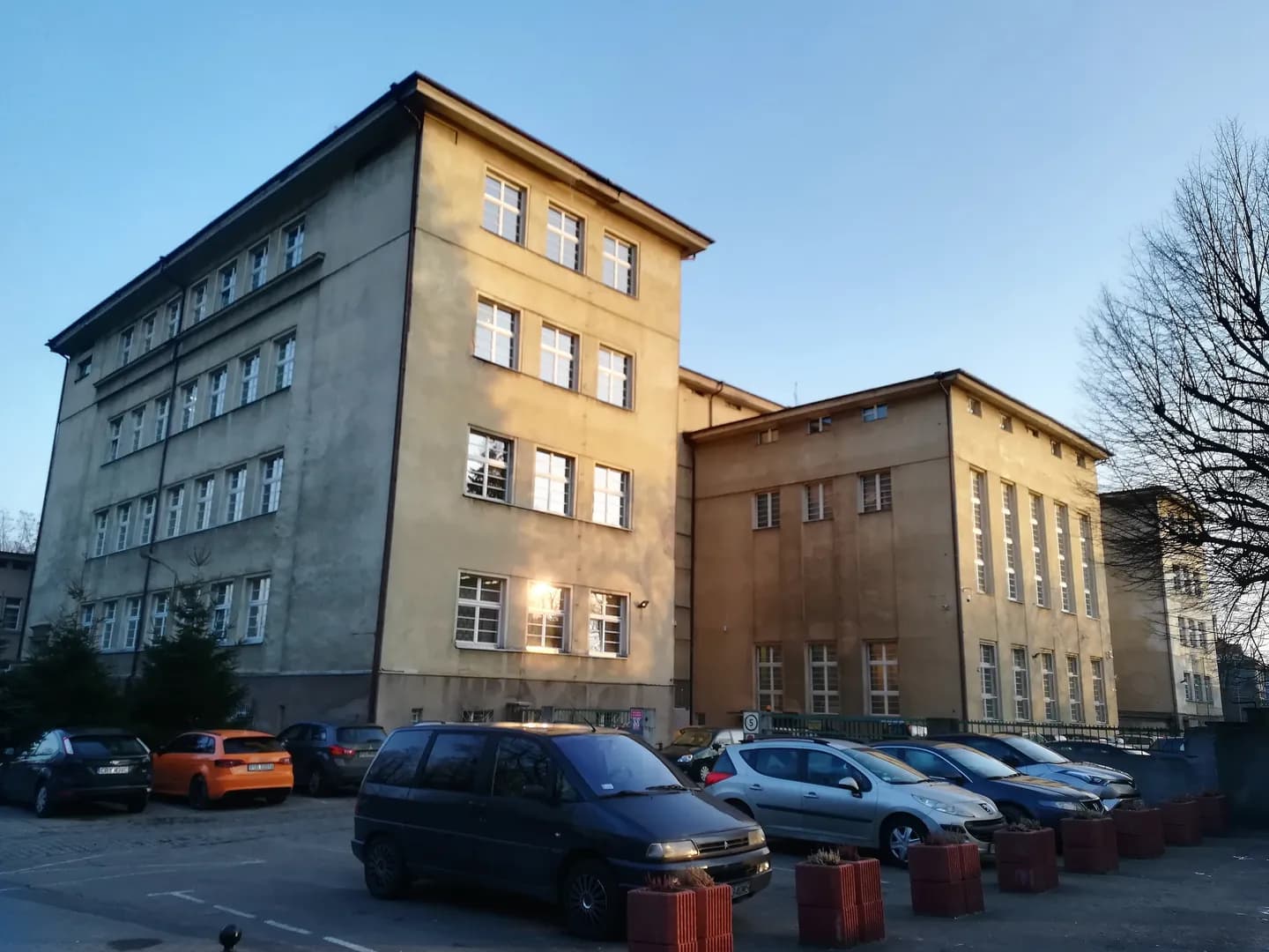 Budynek szkoły od strony ulicy Stolarskiej z parkingiem na pierwszym planie