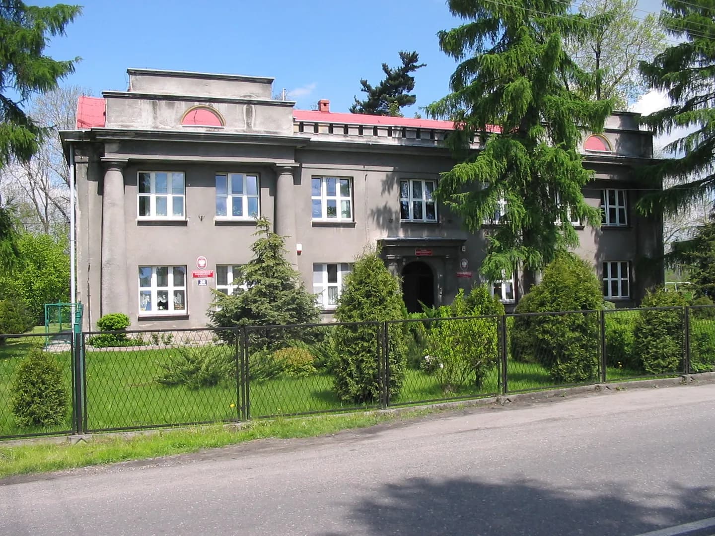 Budynek Zespołu Szkolno-Przedszkolnego w Harmężach widziany zza ogrodzenia