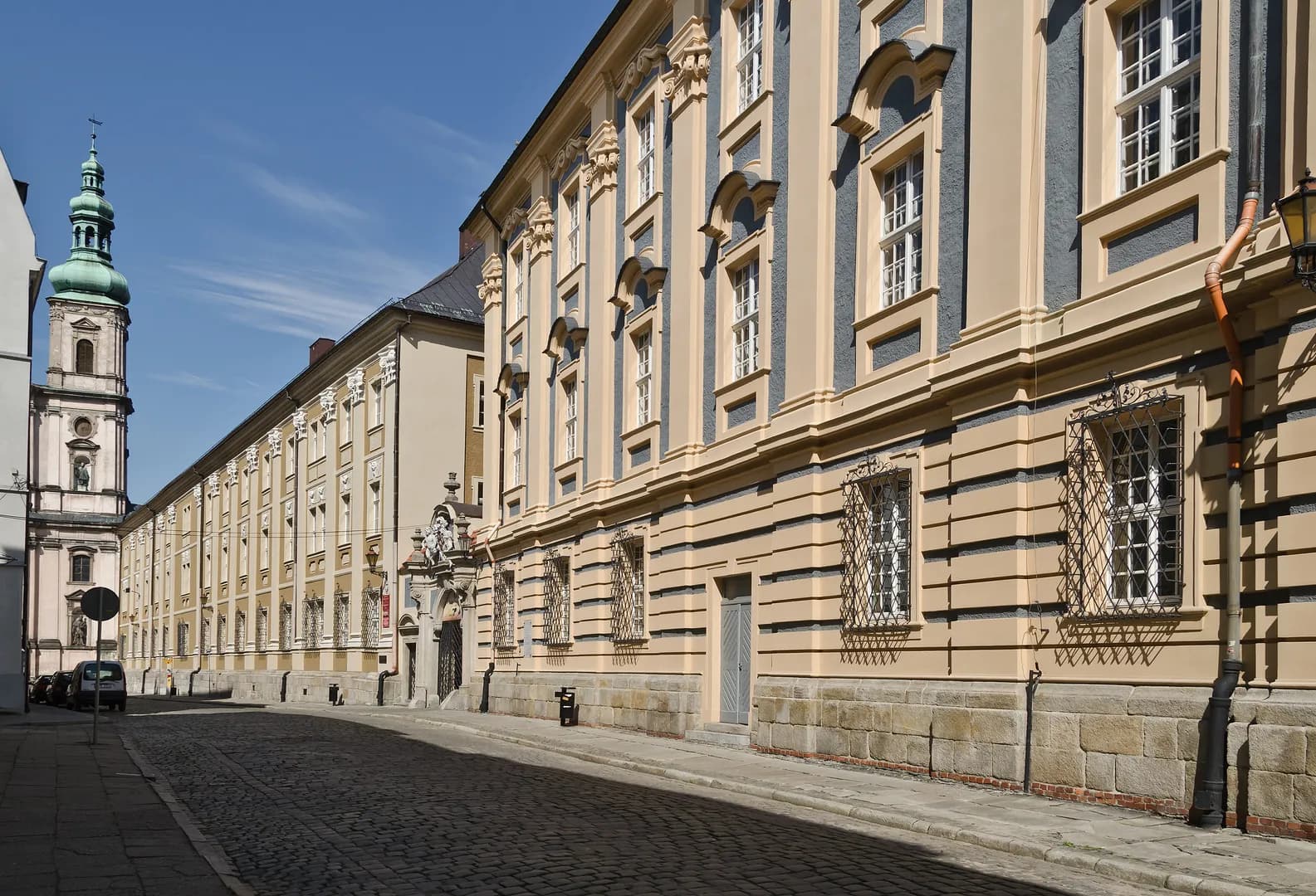 Zabytkowa fasada I Liceum Ogólnokształcącego Carolinum w Nysie przy brukowanej ulicy.