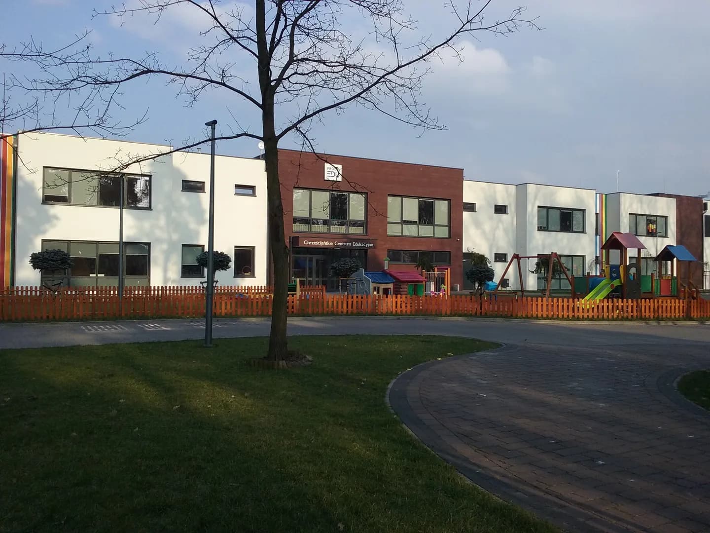 Nowoczesny budynek centrum edukacyjnego z placem zabaw i ogrodzeniem